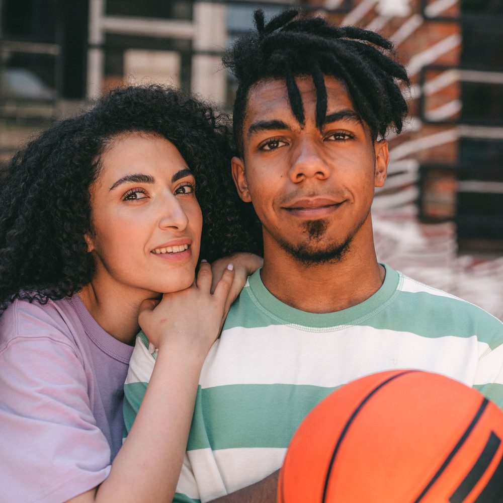 Two parents together on an outdoor court with a basketball