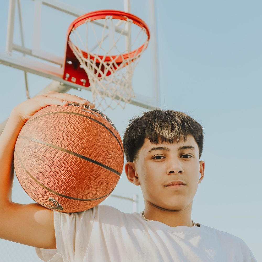 A young player holding a basketball under the rim