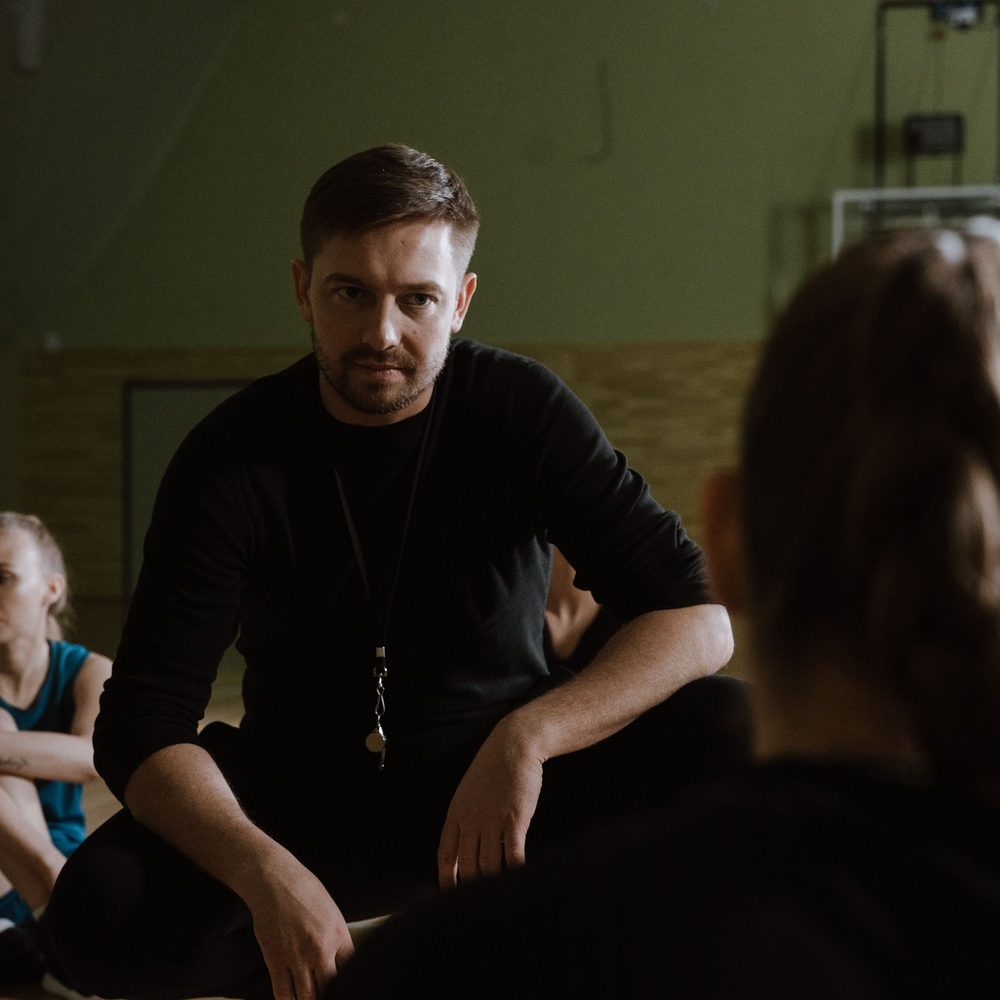 A coach talking through a session with his athletes on the gym floor